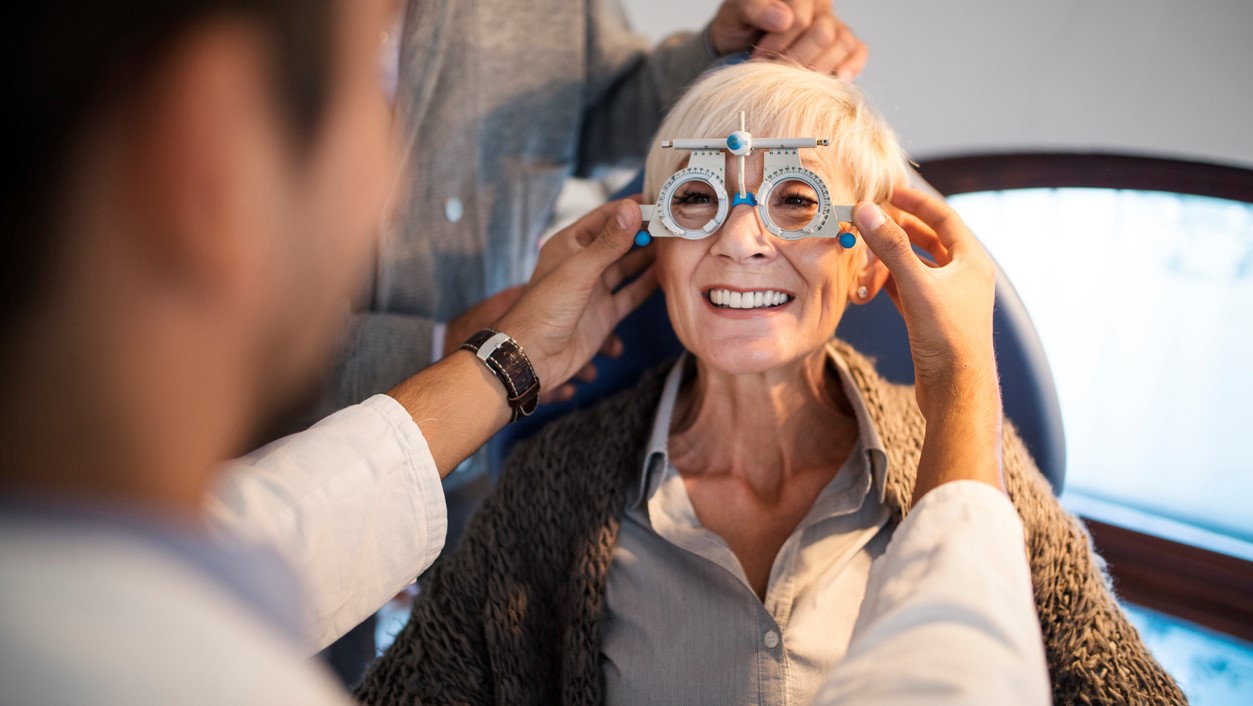 Ældre kvinde smiler mens hun er til øjentjek hos optiker