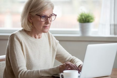 Ældre kvinde med briller arbejder ved computer