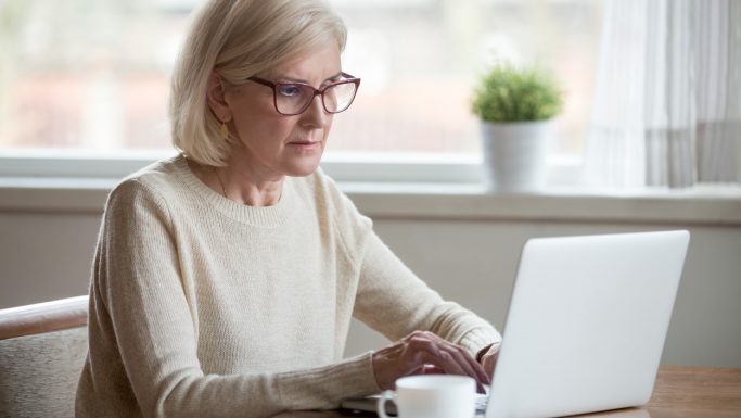 Ældre kvinde med briller arbejder ved computer