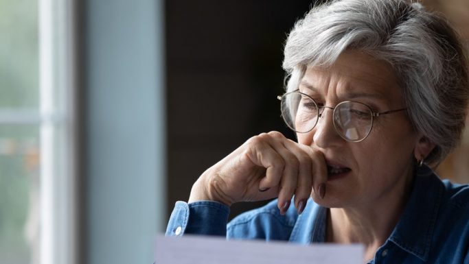 Senior kvinder med briller ser på dokument og ser eftertænksom ud