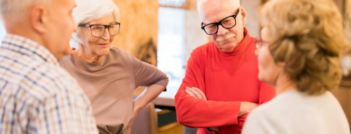 Seniorer med briller står i rundkreds og netværker