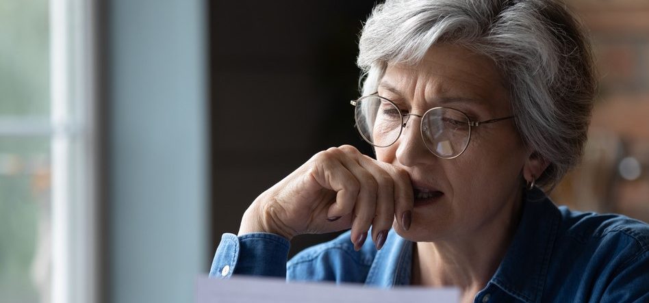 Senior kvinde ser eftertænksomt på papir