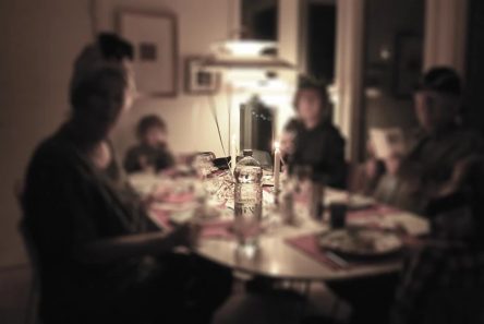 Familie ved aftensmåltis set sløret og med lav belysning over bordet