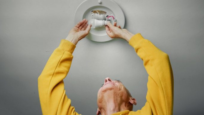 Senior mand ordner belysning i loft