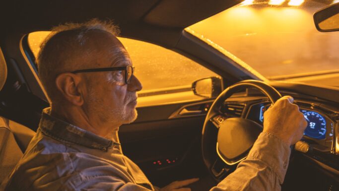 Senior mand kører bil i mørke